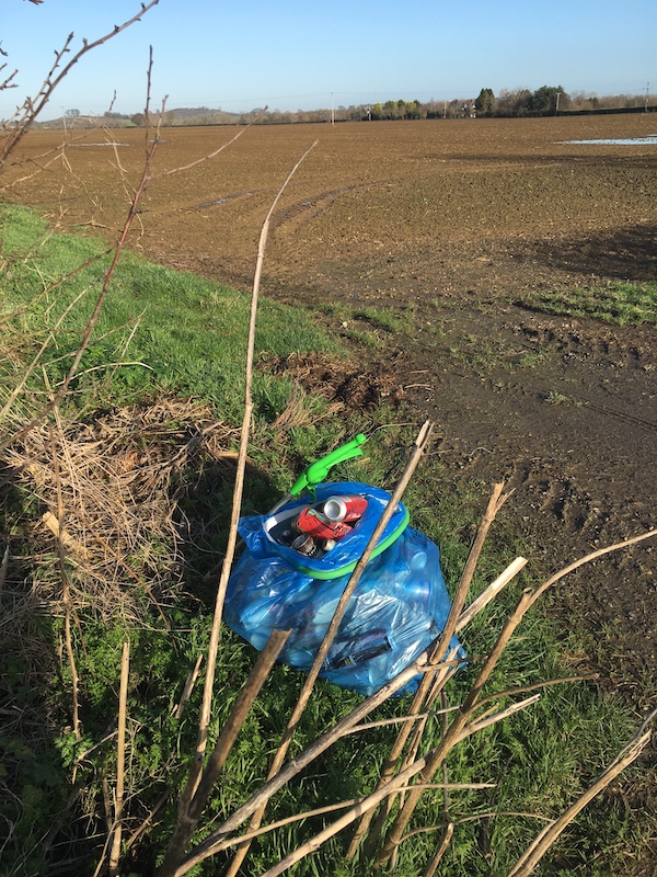 Blue recycleables bag, alongside the Dumbleton Road.