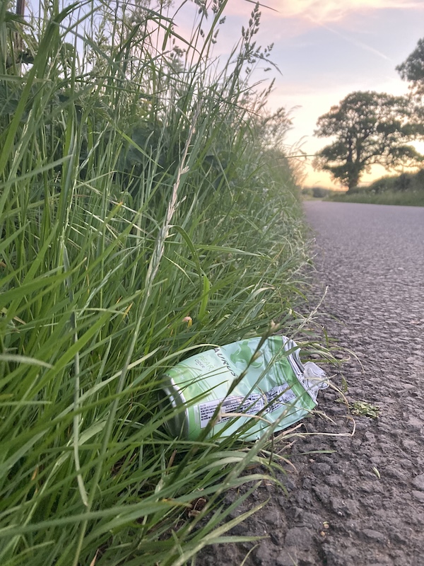 May 29, 2025: Squashed Taurus Pear Cider can on the roadside, looking towards Dumbleton and the sunset